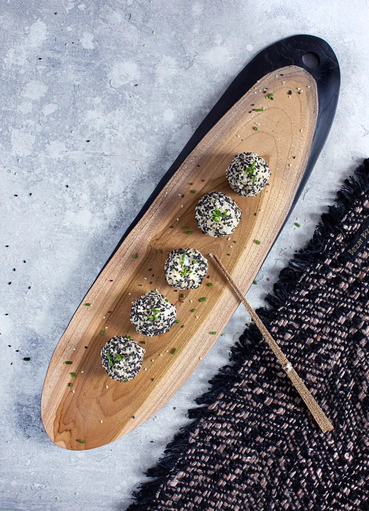 Boules de fromage enrobées de sésame sur un plateau en bois pour Le set table Oh My Gee