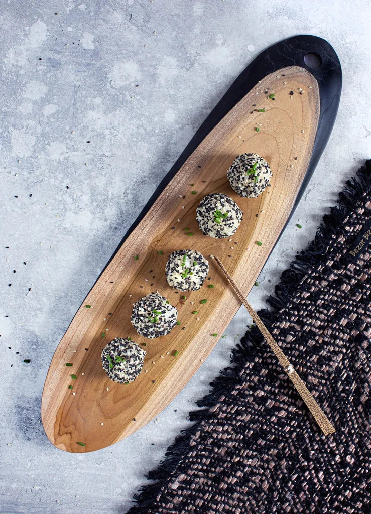 Boules de fromage enrobées de sésame sur un plateau en bois avec Le Set Table Oh My Gee