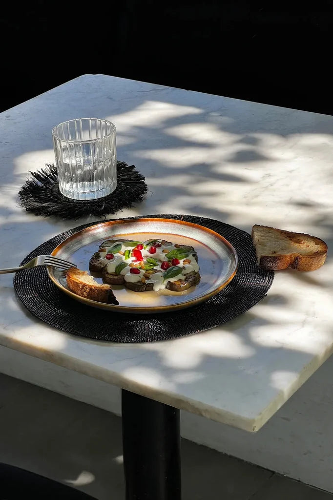 Plaque de présentation Le set de table perlé Noir_40 avec un plat d’aubergine et graines de grenade