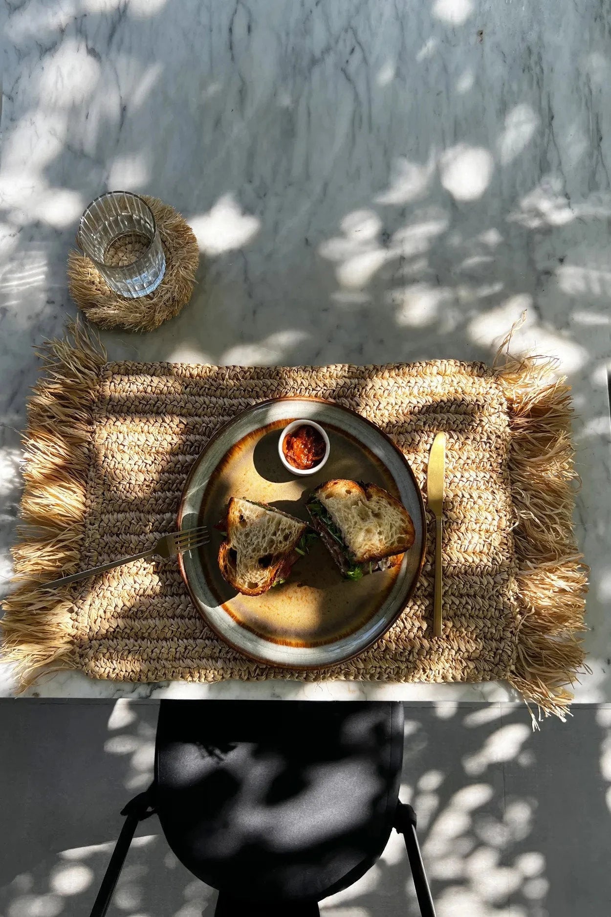 Set de table en raphia naturel à franges avec sandwich sur une assiette rustique