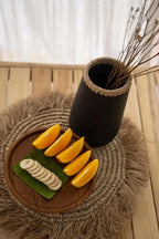 Assiette en raphia de seagrass avec tranches de banane et quartiers d’orange