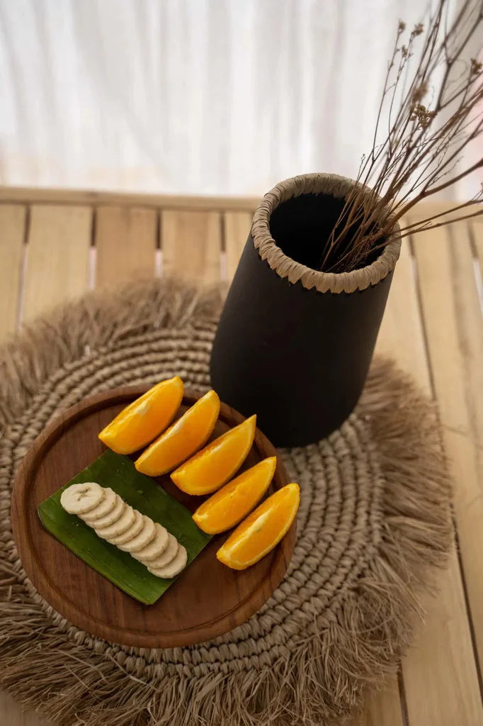 Assiette en raphia de seagrass avec tranches de banane et quartiers d’orange