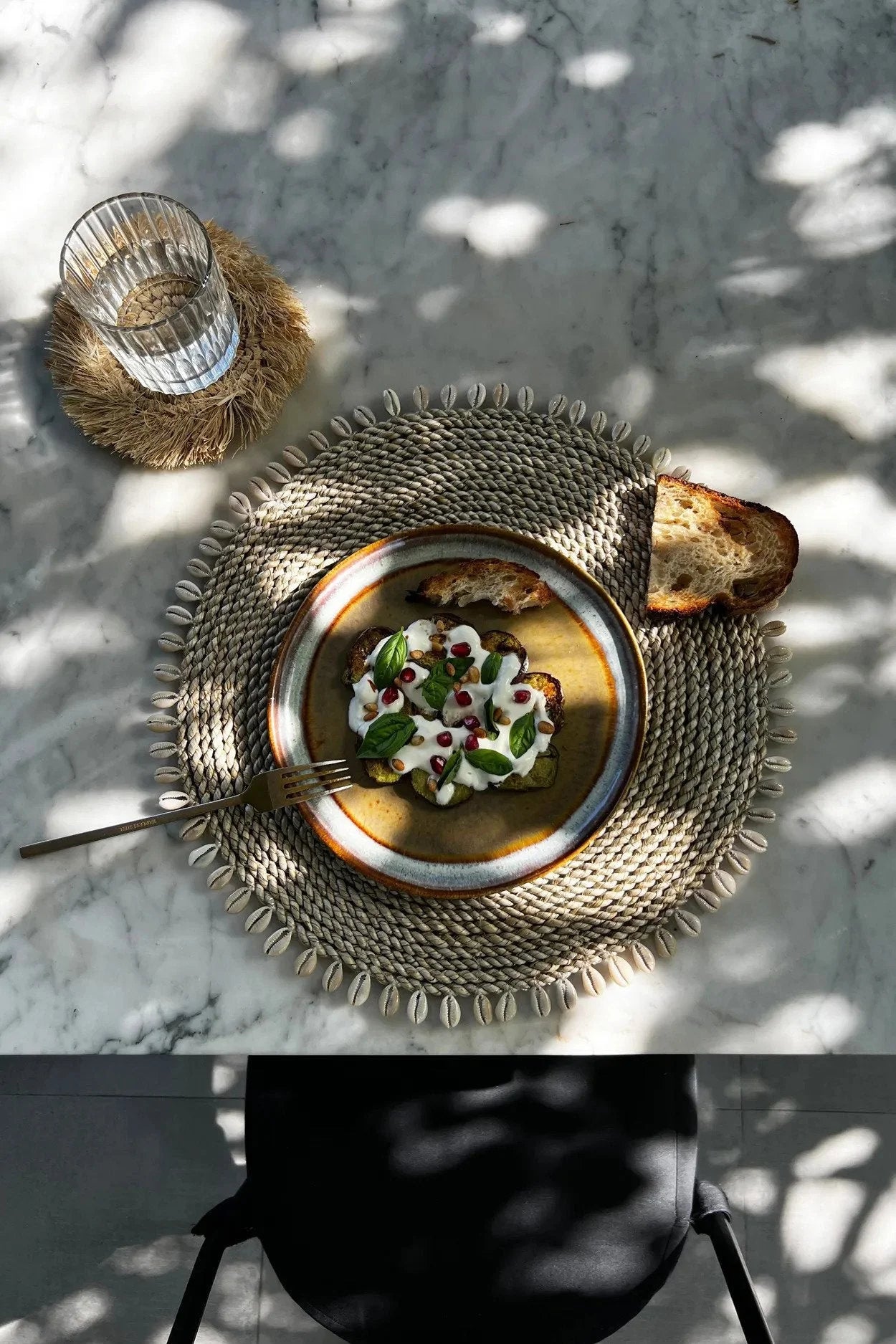 Plat joliment présenté avec pain sur le set de table rond en jonc de mer avec coquillages naturels