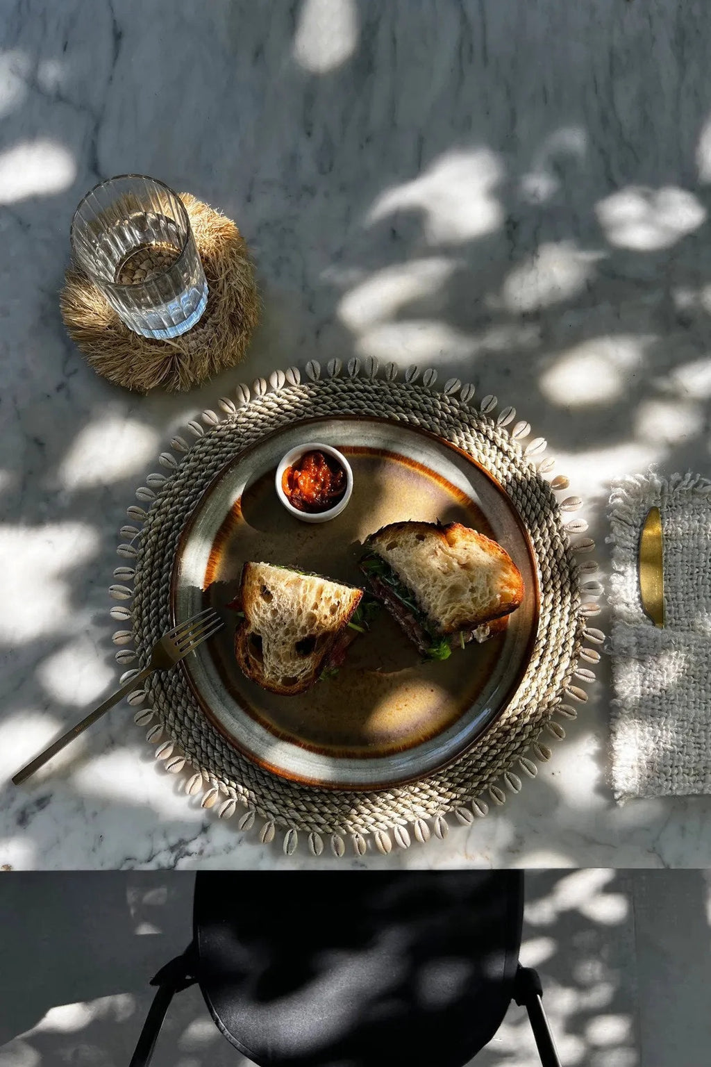 Sandwich artisanal sur une assiette décorative du Set de table rond en jonc de mer avec coquillages naturels