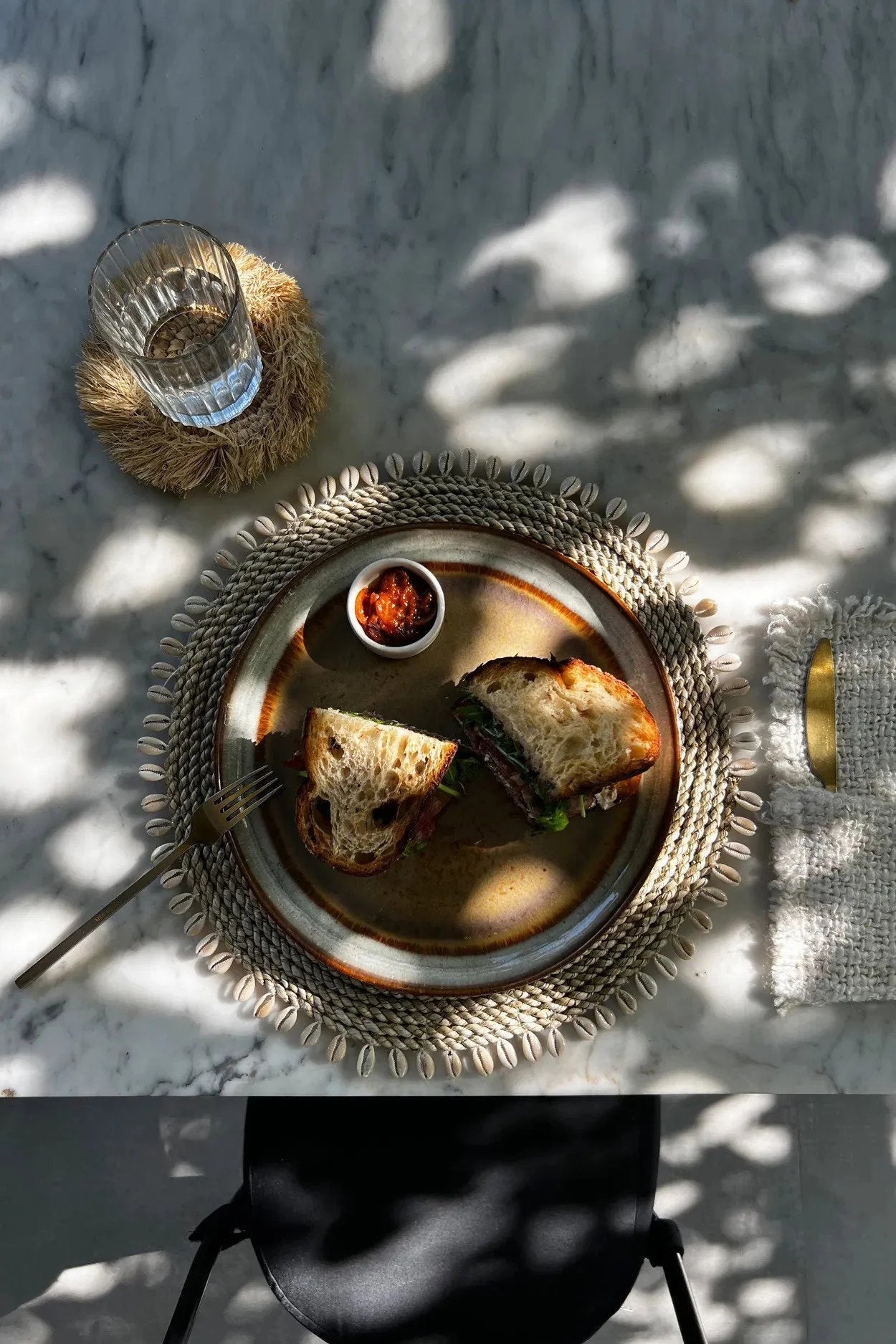 Sandwich artisanal sur une assiette décorative du Set de table rond en jonc de mer avec coquillages naturels
