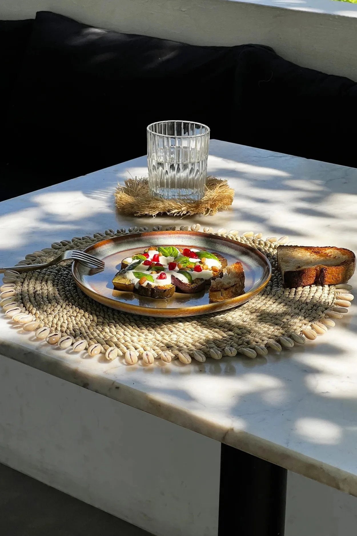 Bruschetta sur une assiette avec un verre d’eau, service rond en jonc de mer coquillages