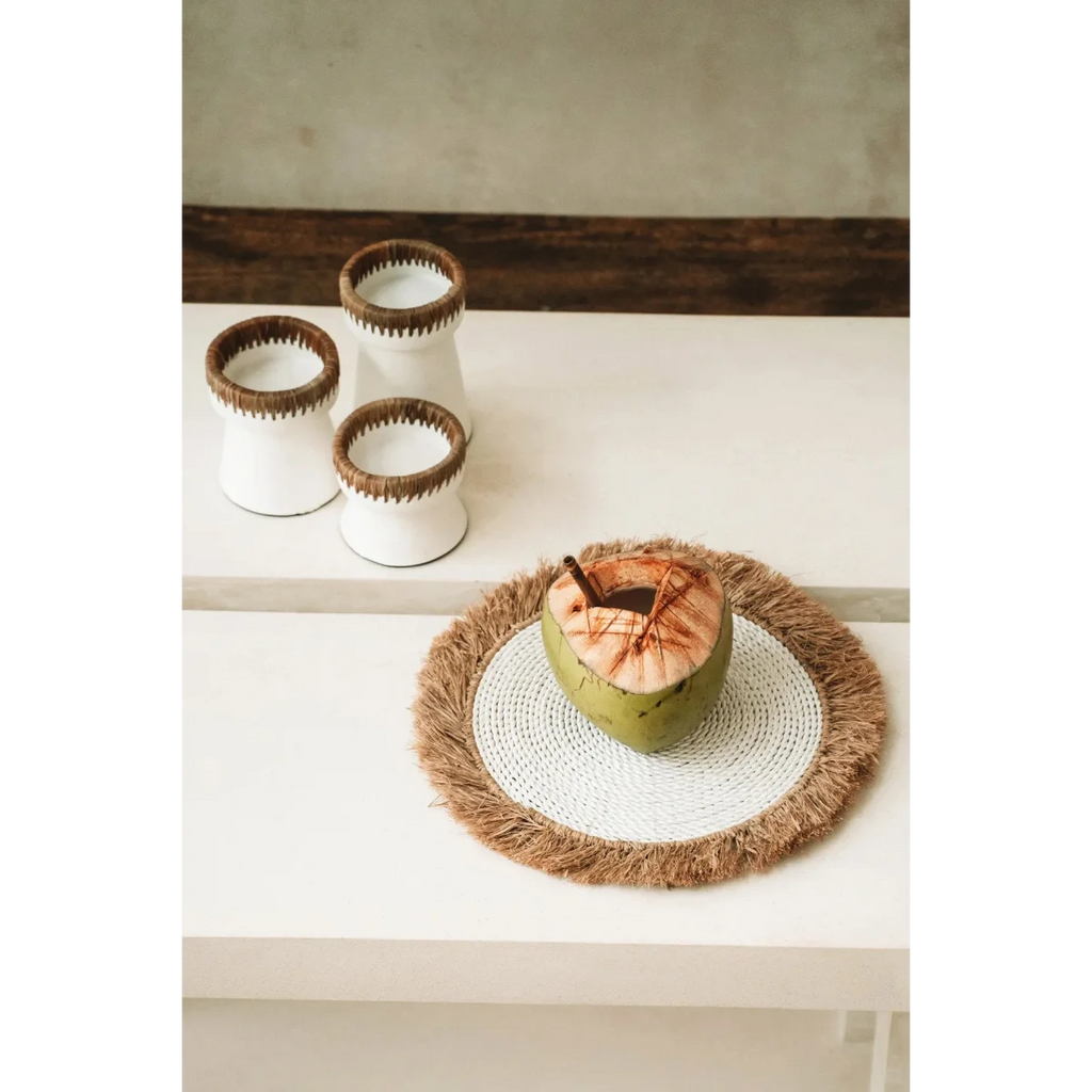Cocotier frais avec boisson dans un set de table rond en raphia et herbe marine blanc naturel