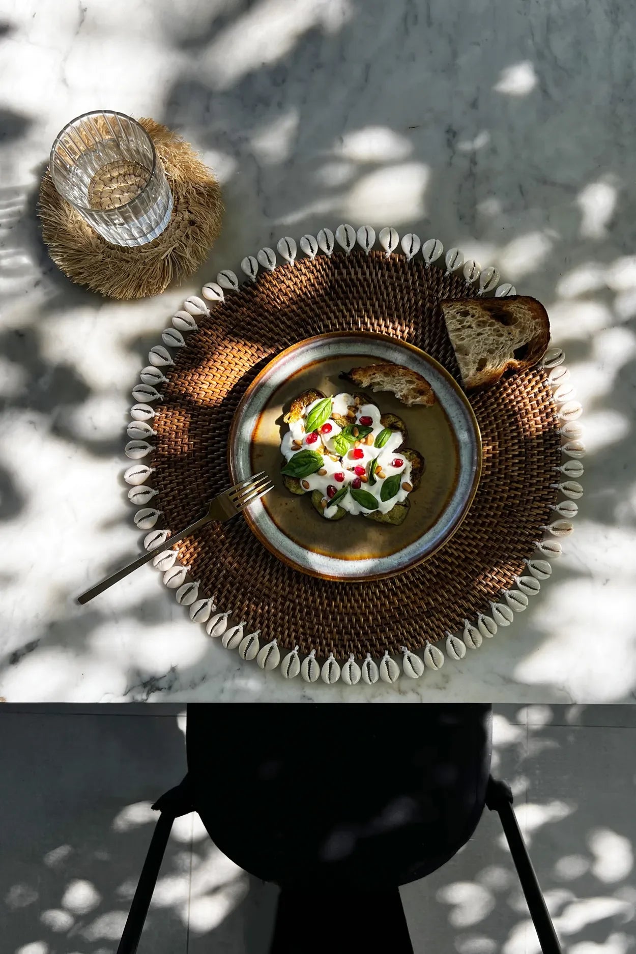 Assiette en rotin marron avec bordure de coquillages cauris et soupe artistiquement présentée