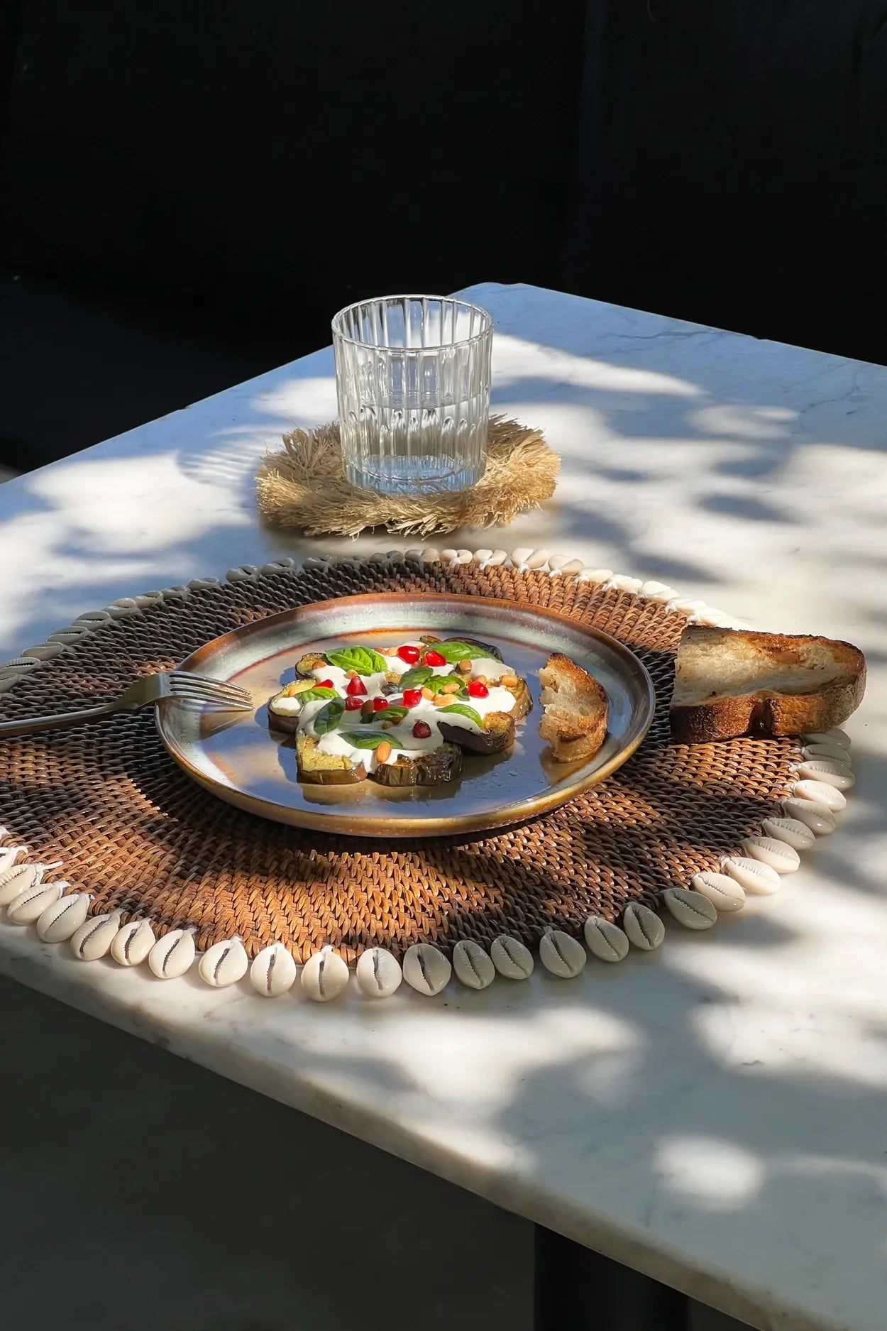Assiette petit-déjeuner avec toast et verre d’eau sur un set de table rond en rotin marron