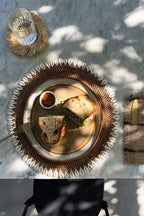 Sandwich présenté sur une assiette rotin marron avec bordure de coquillages cauris