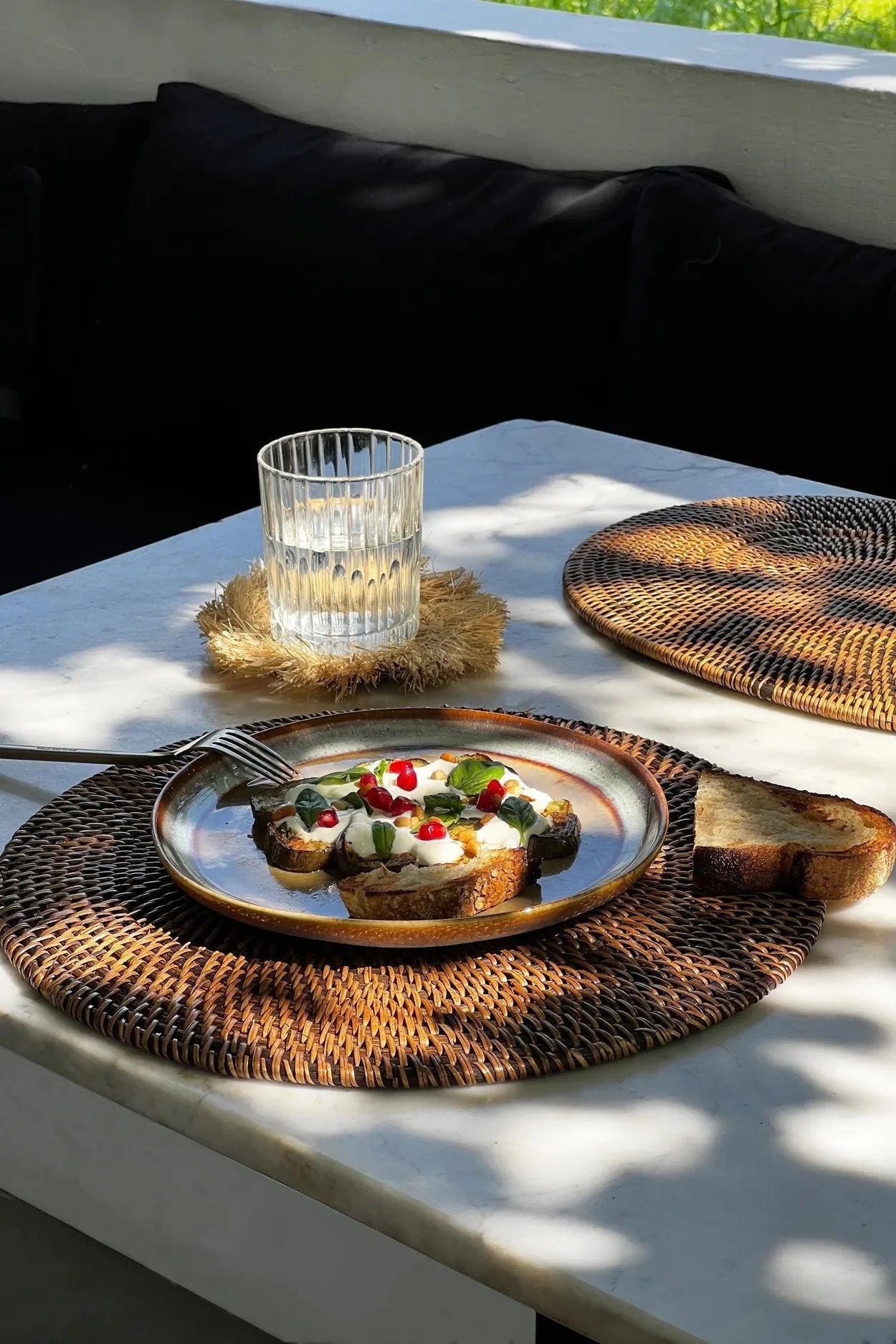Assiette petit-déjeuner avec toast et garnitures sur set de table en rotin tressé marron naturel