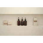 Set de trois bouteilles pompe foncées et objets décoratifs en céramique sur une étagère