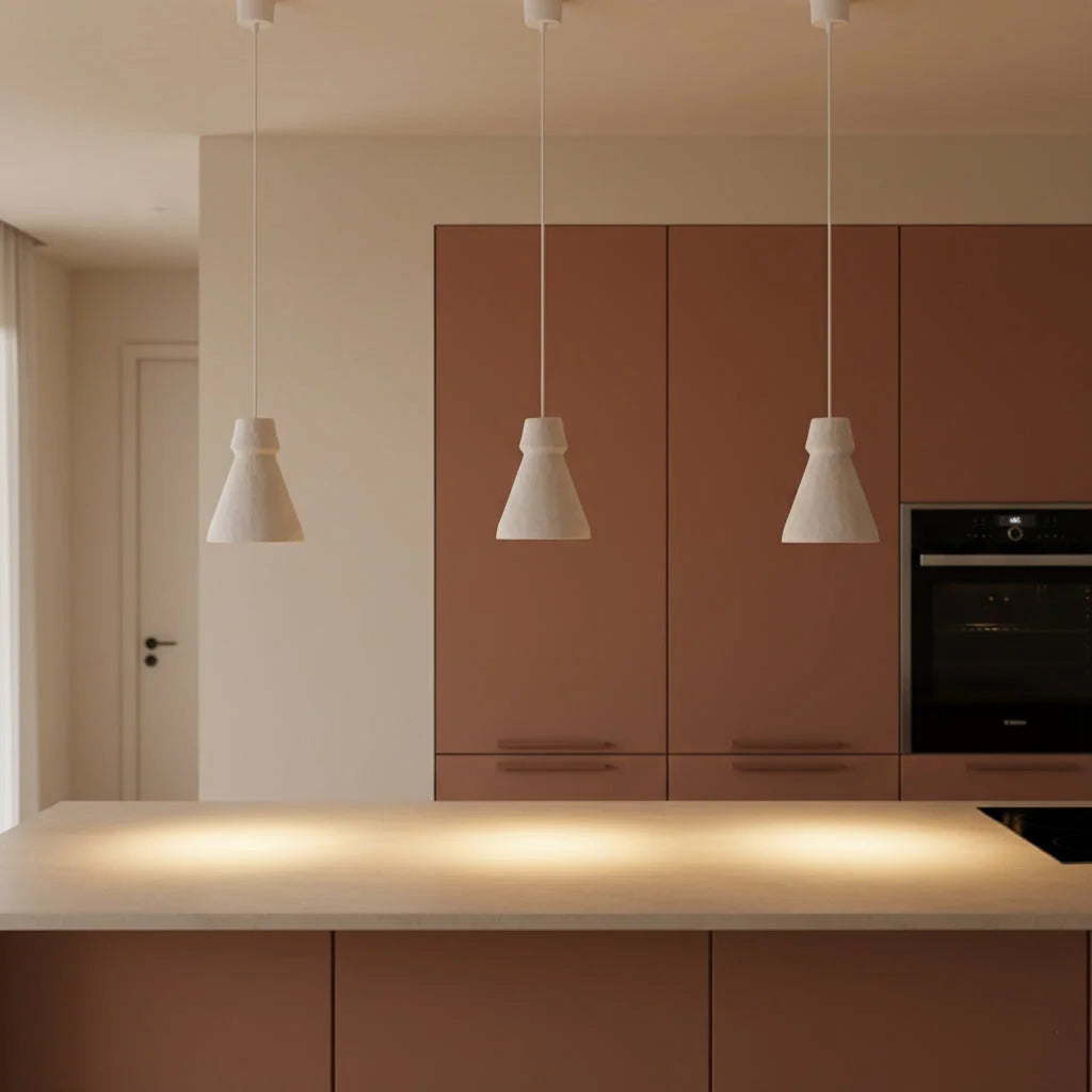 Trois suspensions artisanales en papier-mâché blanc cassé au-dessus d’un îlot de cuisine