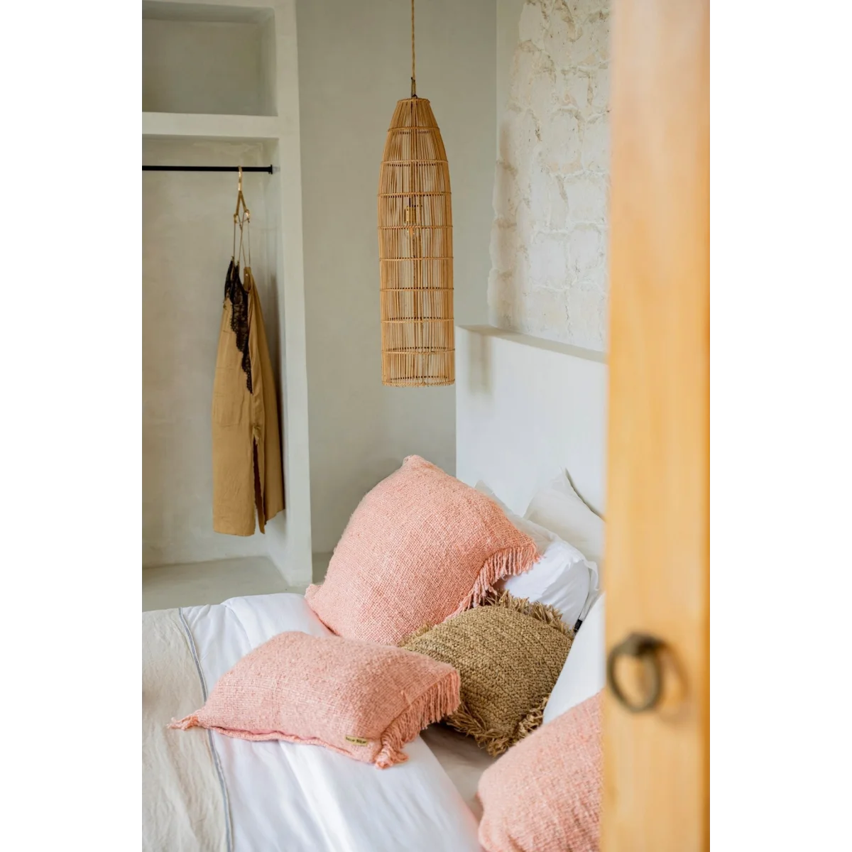 Coussin décoratif sur un lit avec plusieurs oreillers, idéal pour la Suspension cylindrique en rotin naturel ajouré 90x23 cm
