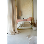 Miroir pleine longueur avec cadre en or refletant un lit avec literie rose