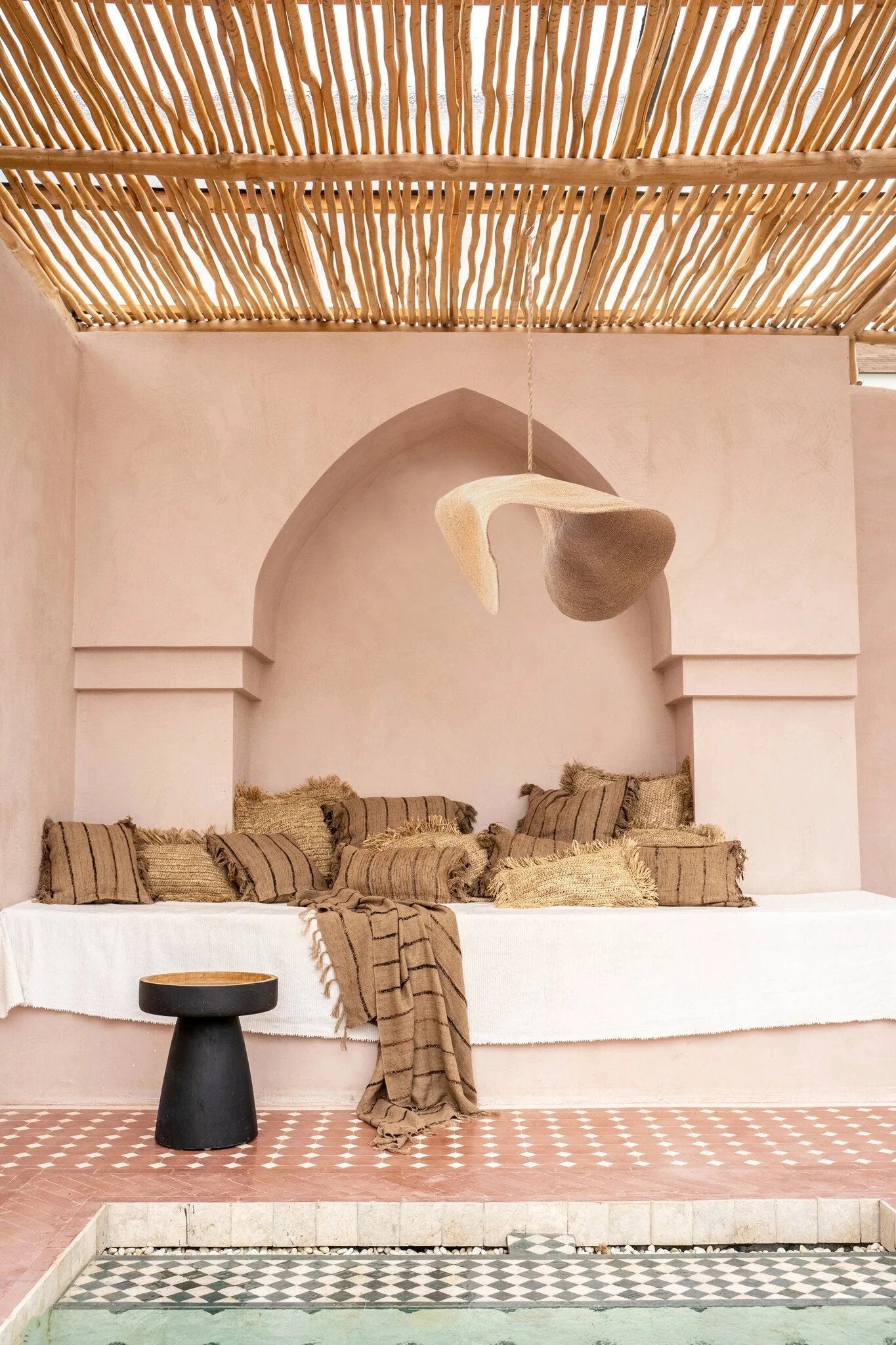 Espace de détente marocain avec coussins rayés et suspension en fibre tressée beige sable