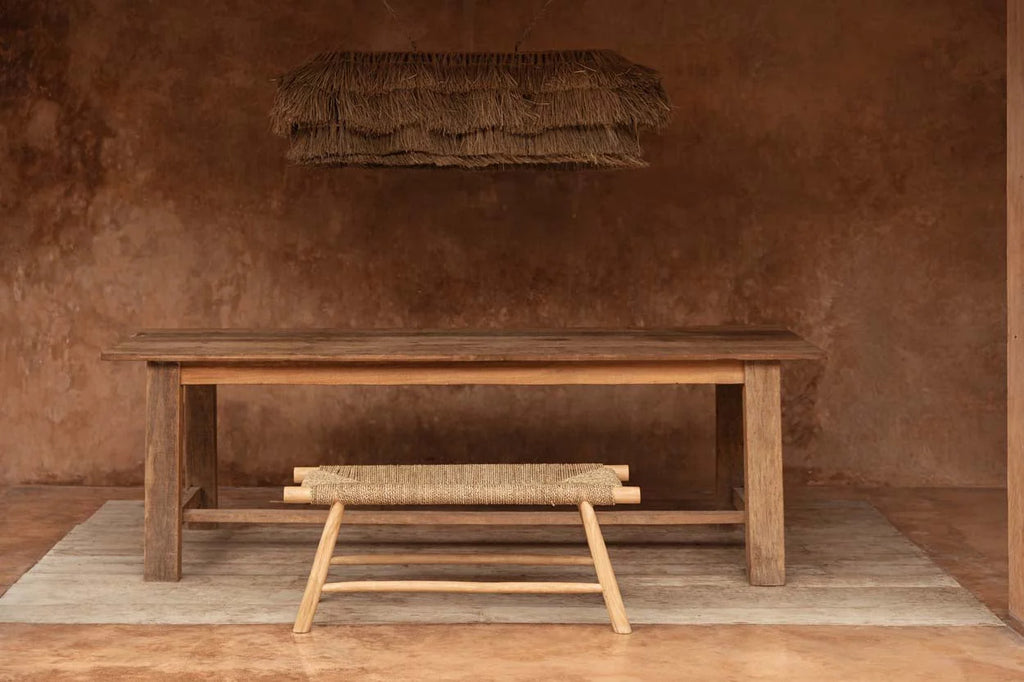 Table rustique en bois avec banc en jonc et suspension frangée en fibres naturelles beige paille au-dessus