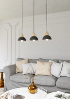 Trois suspensions linéaires en métal noir et bois au-dessus d’un sofa gris