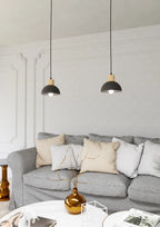 Deux suspensions noires en dôme métal et bois clair au-dessus d’un sofa gris