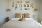 Coussin en rotin naturel ajouré avec literie neutre sur un lit élégant