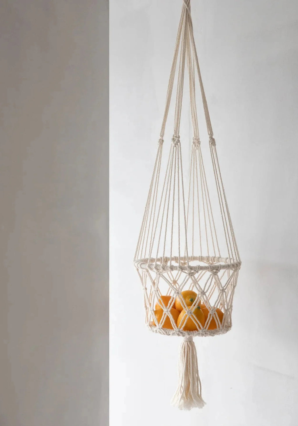 Support à fruits en macramé coton blanc avec pompon décoratif et oranges suspendues