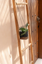 Échelle en bois avec plante suspendue dans le porte-plante ronde en feuille de bananier tressée noire