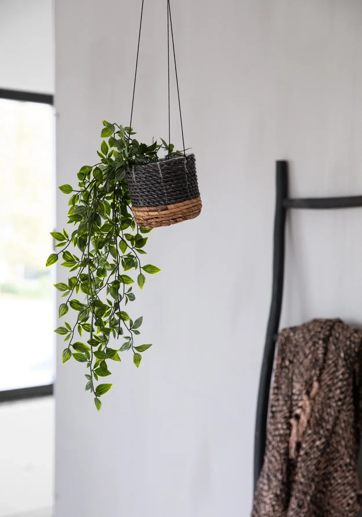 Plante suspendue dans un pot tressé rond en feuille de bananier noir