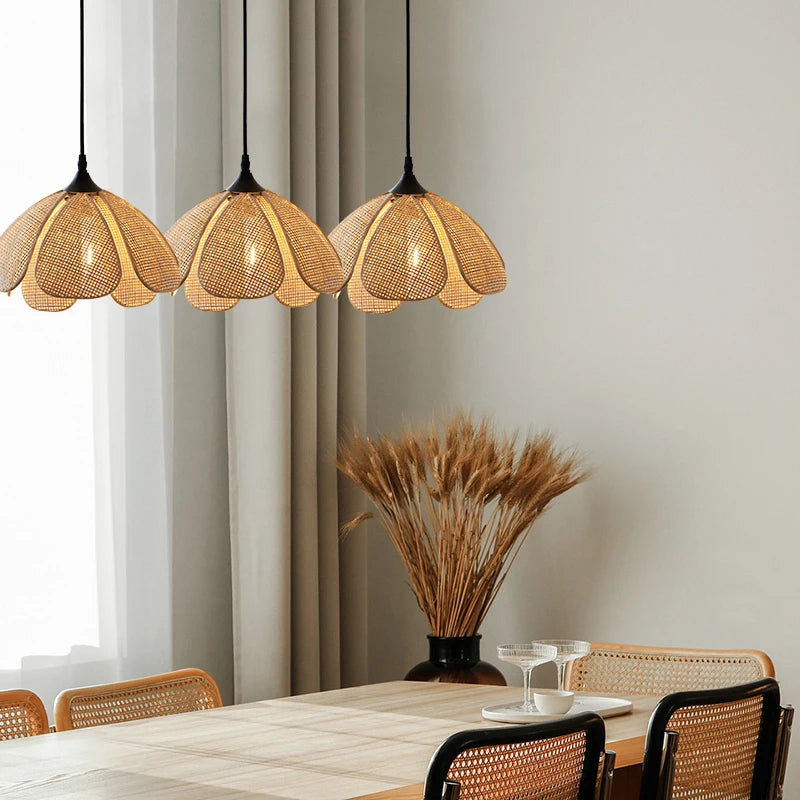 Suspension rotin à 3 lampes installée au-dessus d'une table à manger moderne.