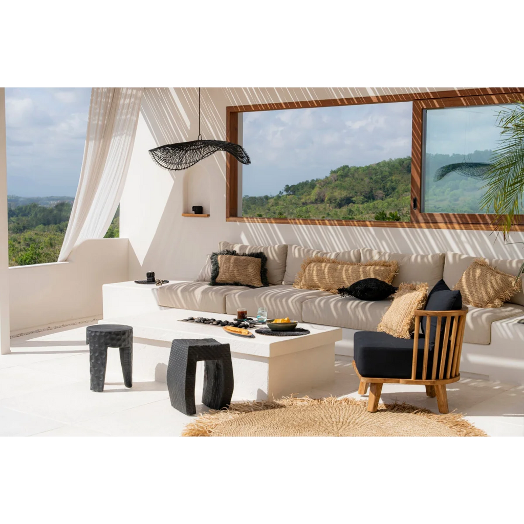 Coin salon extérieur avec canapé modulable clair, fauteuil foncé, table blanche et tabourets