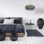 Intérieur de chambre rustique avec suspension en rotin tressé noir et bois clair ovale Ø60 cm