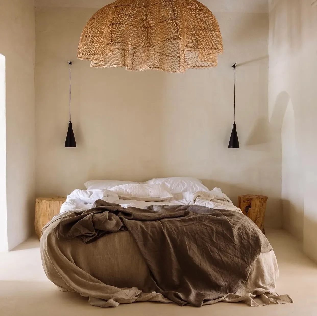 Suspension XXL en rotin naturel tressé ajouré dans une chambre minimaliste chaleureuse