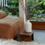 Vase céramique crème avec branches de bourgeons blancs sur table basse en bois de manguier brun sculpté 40x25 cm