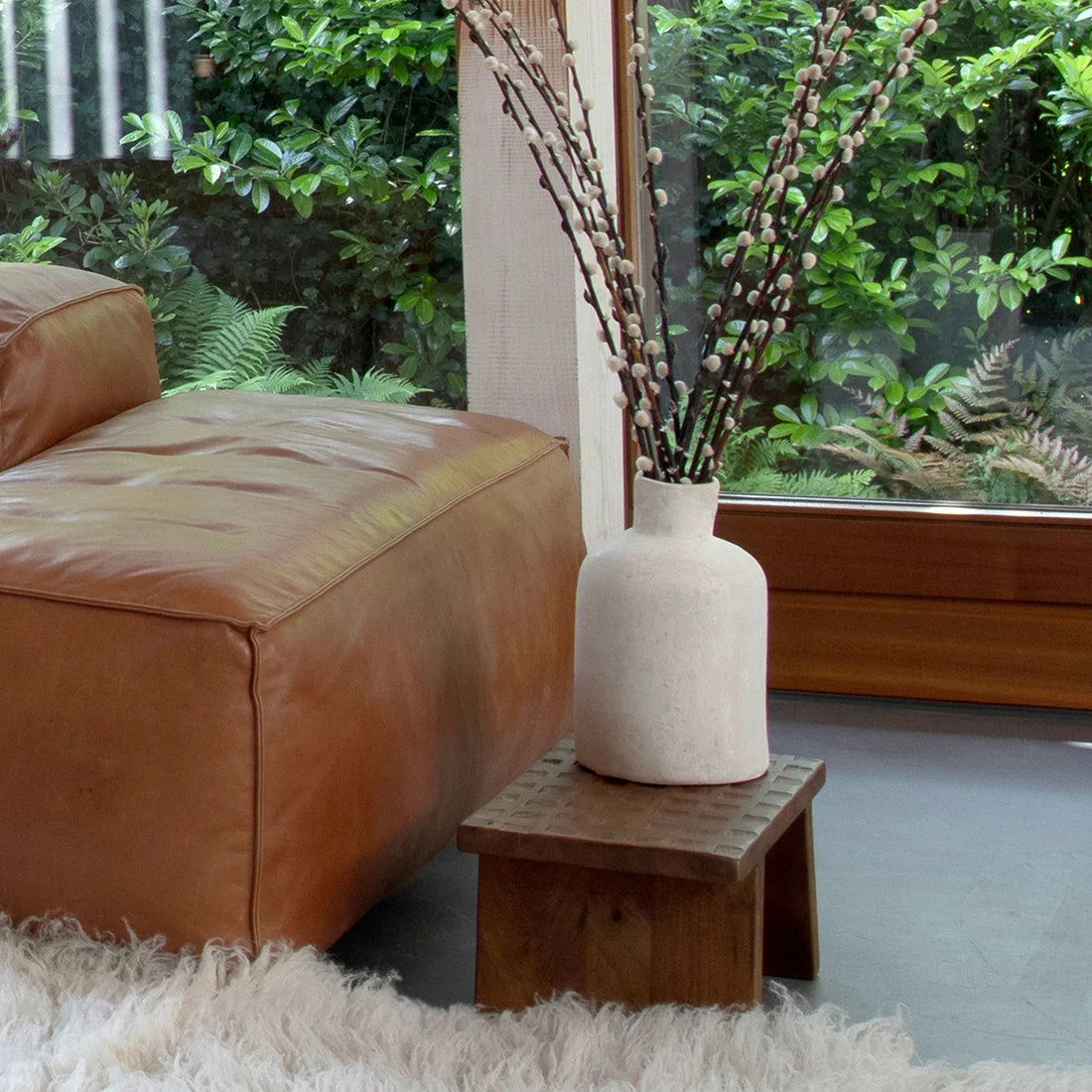 Vase céramique crème avec branches de bourgeons blancs sur table basse en bois de manguier brun sculpté 40x25 cm