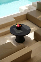 Table basse noire ronde avec un bol de fruits, design moderne et élégant