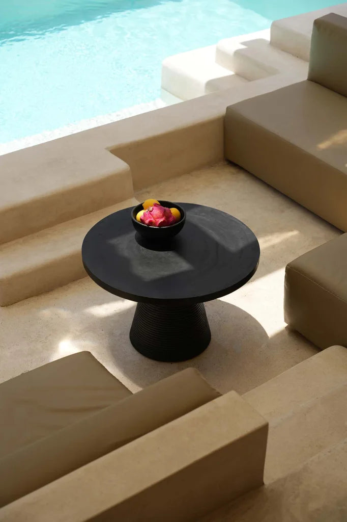 Table basse noire ronde avec un bol de fruits, design moderne et élégant