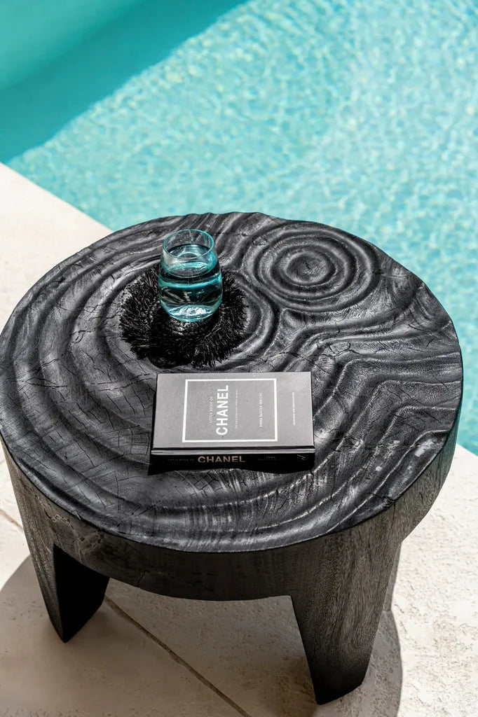 Table basse Madero Noir avec verre d’eau et livre Chanel sur le dessus