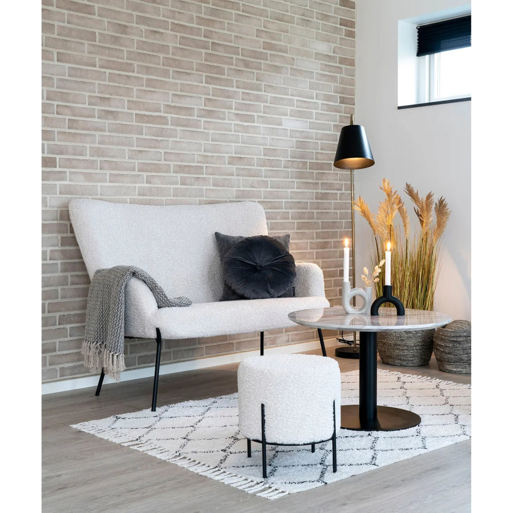 Fauteuil blanc texturé aux pieds noirs, avec plaid gris drapé