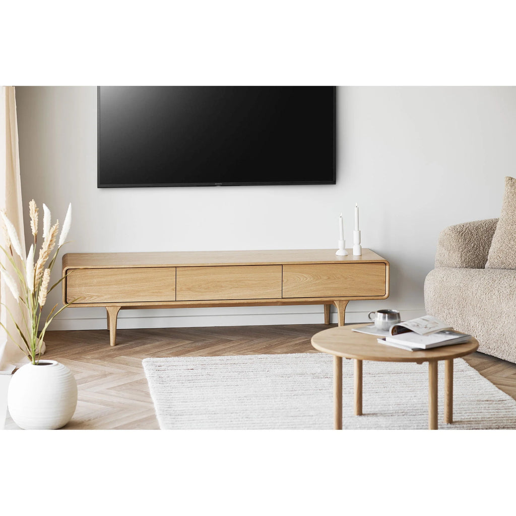 Meuble TV rond en chêne naturel avec trois tiroirs et pieds effilés pour salon
