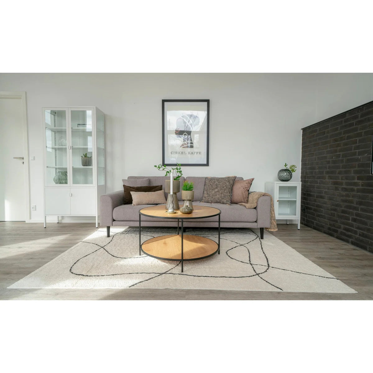 Canapé gris moderne minimaliste avec coussins texturés et table basse ronde bois clair métal noir Ø80 cm