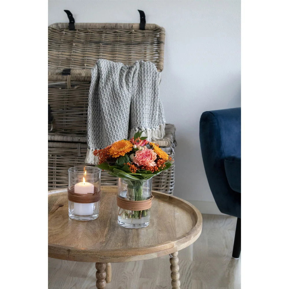 Vase en verre transparent avec bande en osier, bouquet de fleurs colorées, table ronde en bois de manguier