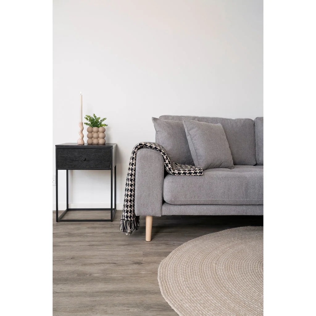Canapé gris avec jeté à motif pour la table de chevet noire en acier et MDF