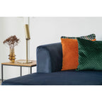 Canapé en velours bleu marine avec coussins orange et vert texturés