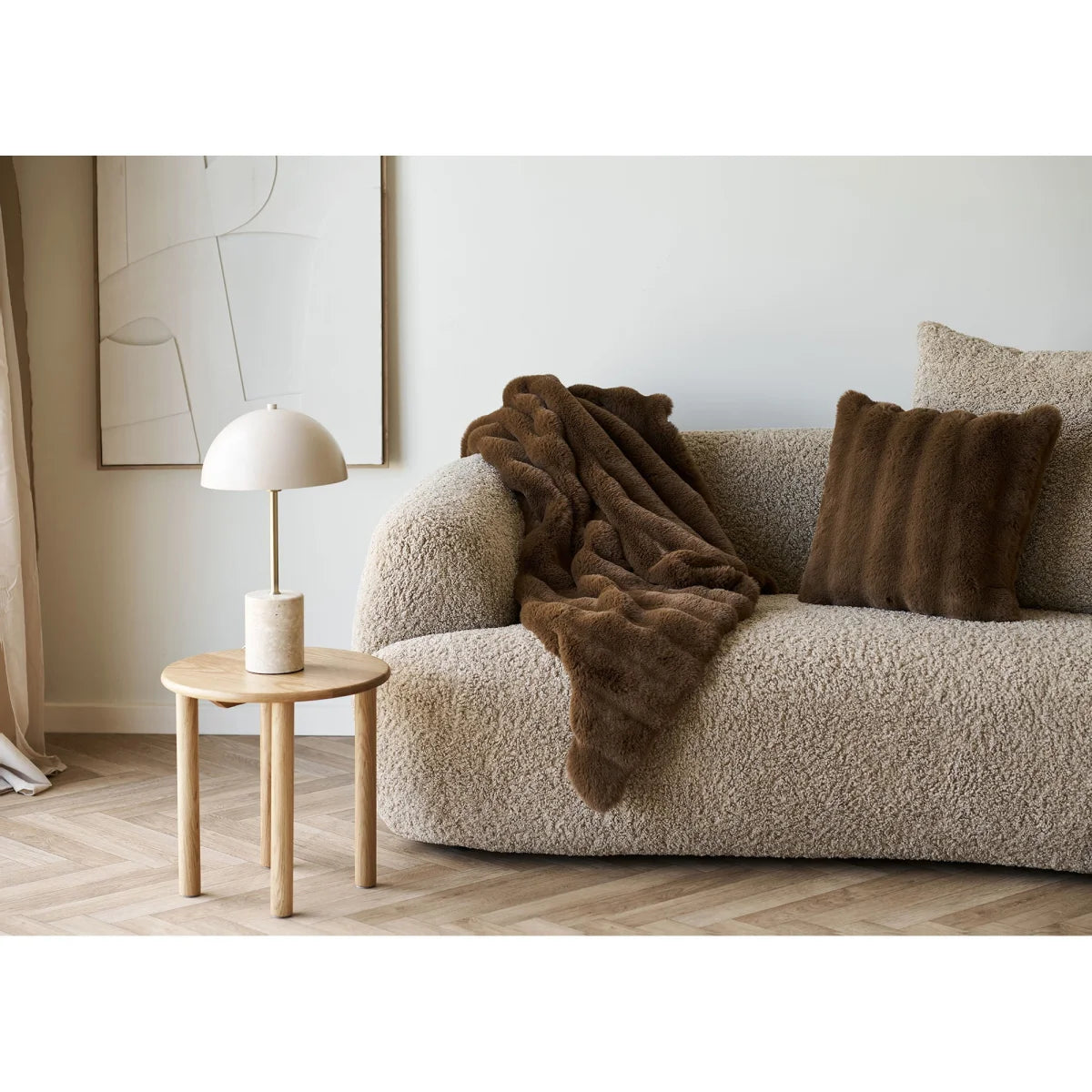 Canapé en boucle beige avec plaid en fausse fourrure marron et coussin dans un salon