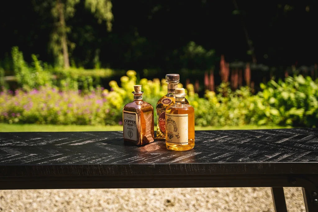 Trois bouteilles de liqueur sur la table haute à chevrons noire de 140cm