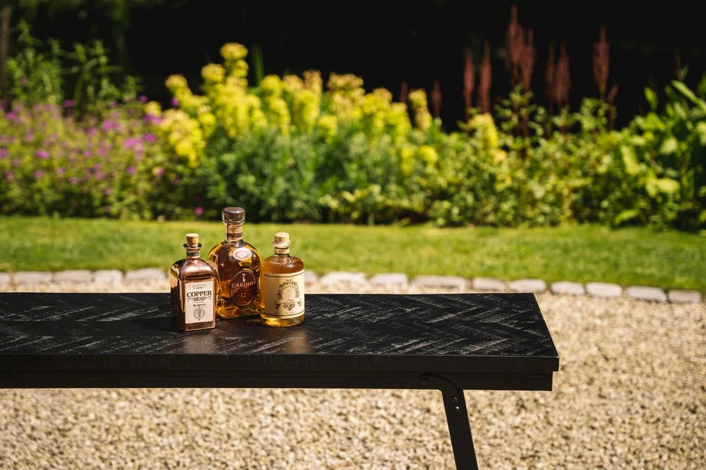 Trois bouteilles de liqueur sur la table haute à chevrons noire 140 cm
