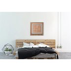 Lit en palette en bois avec une couette noire et des oreillers blancs dans un tableau mural en lin
