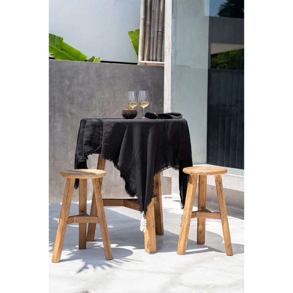 Nappe en lin noir aux bords effilochés sur tabourets en teck recyclé H66 cm