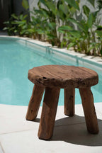 Tabouret bas rond en bois massif artisanal avec trois pieds et surface ronde naturelle