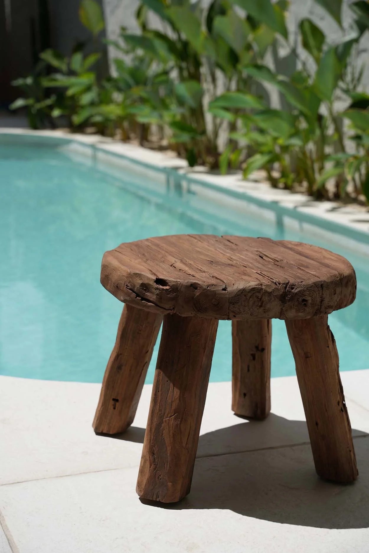 Tabouret bas rond en bois massif artisanal avec trois pieds et surface ronde naturelle