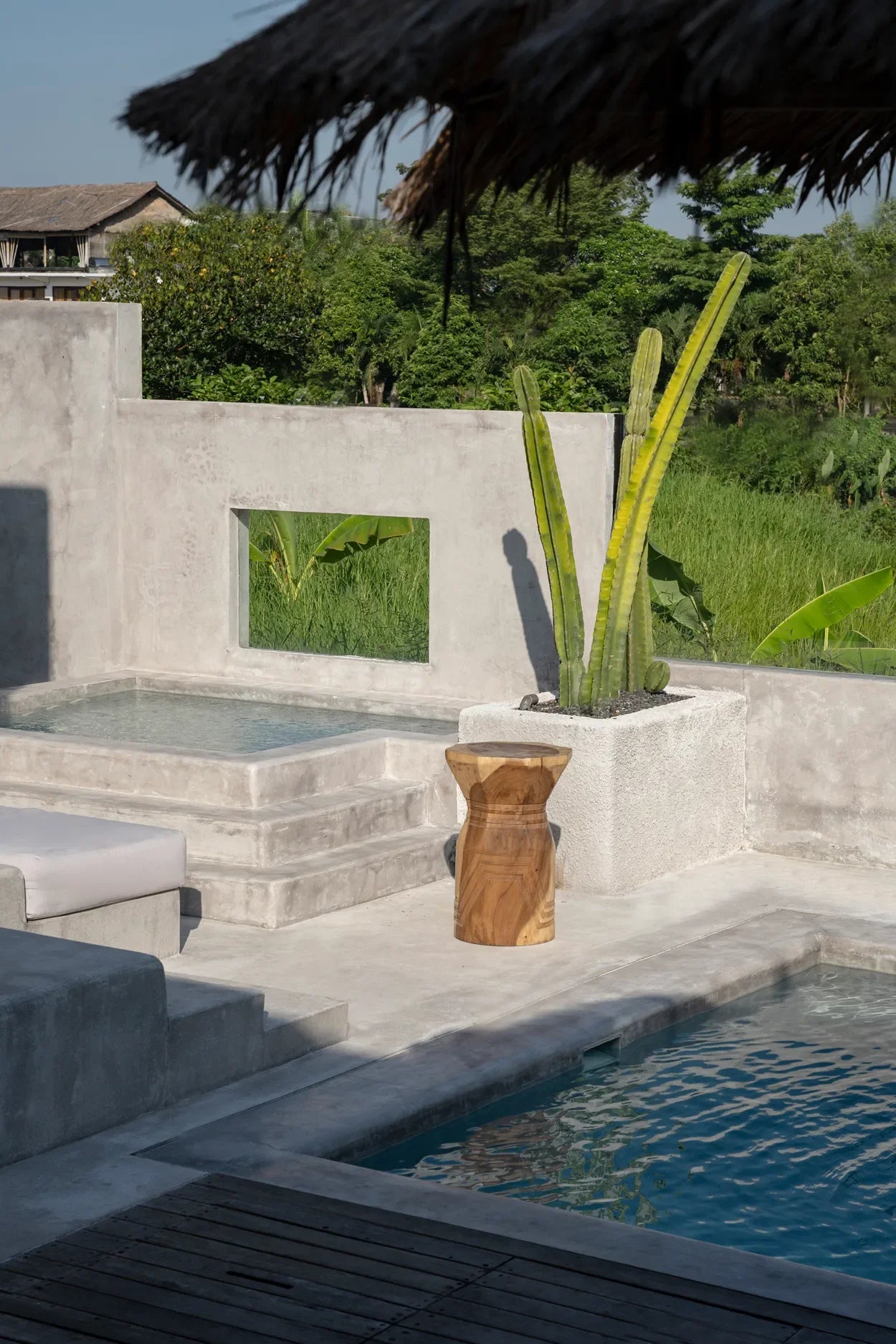 Photo d’un espace piscine en béton avec cactus, associée à un tabouret géométrique en bois de Suar naturel 60 cm